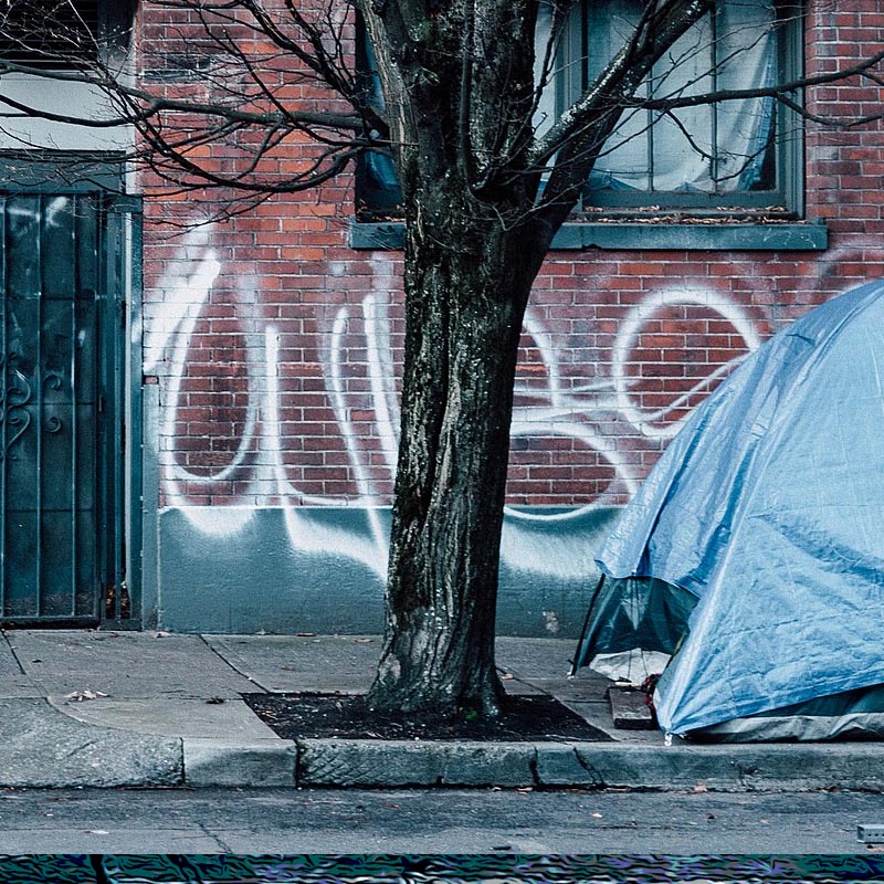 a tent pitched on a Portland sidewalked in front of an abandoned building