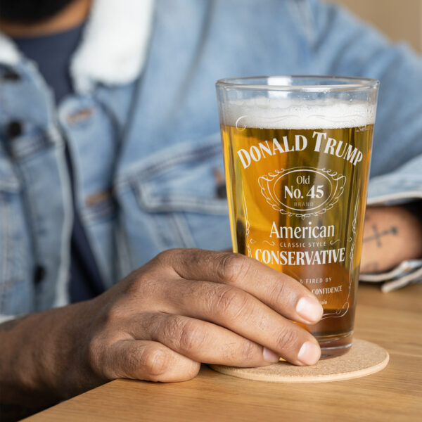 A man in a jean jacket holding our classic "American Conservative" Donald Trump pint glass